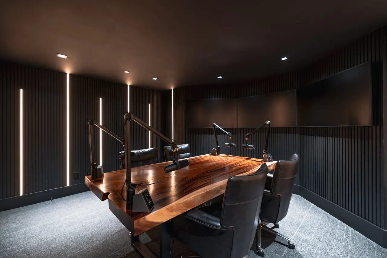 Podcast studio with acoustic slat walls, a live-edge table and boom microphones
