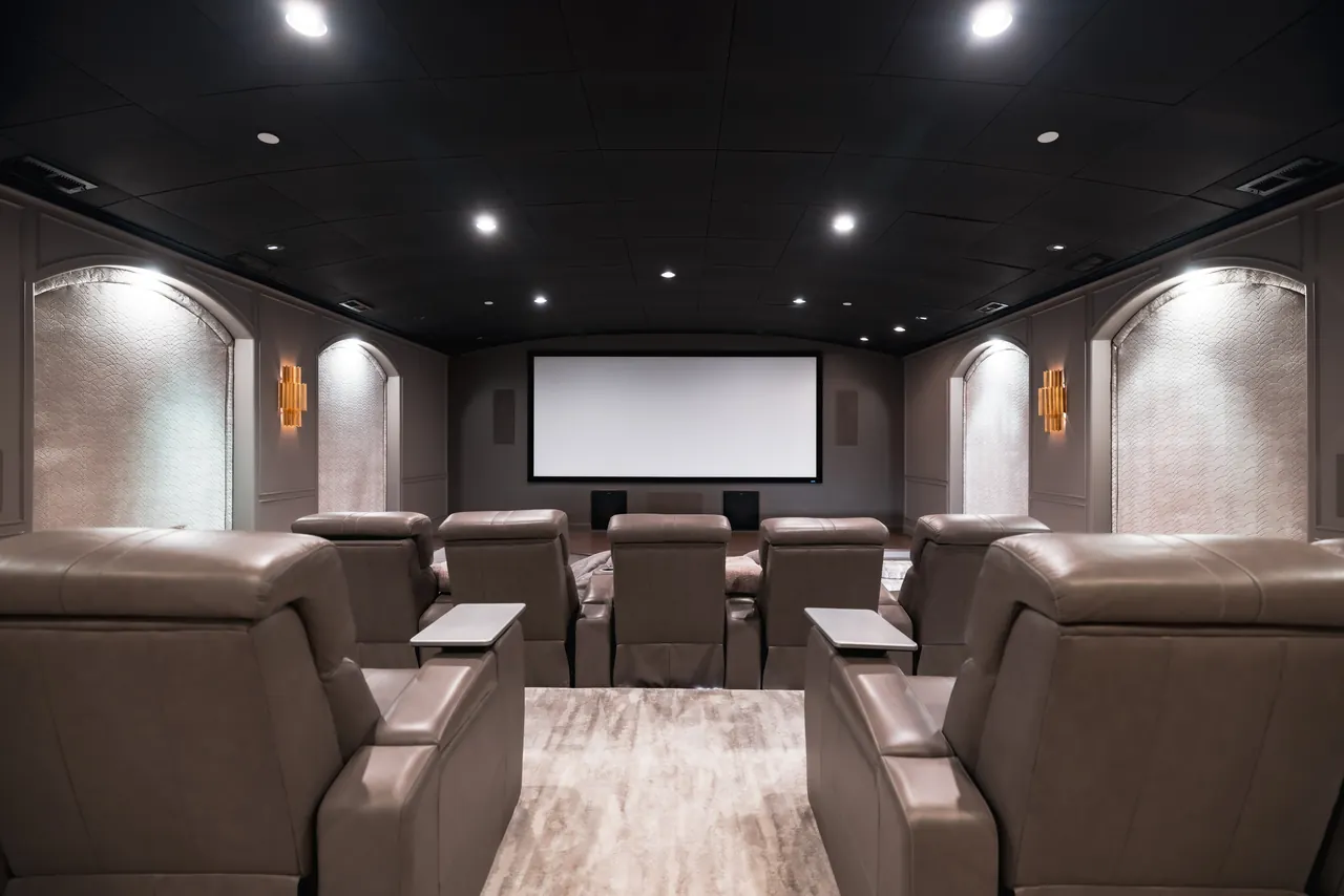 Private home cinema with tiered leather recliners, acoustic wall panels and a wide projection screen