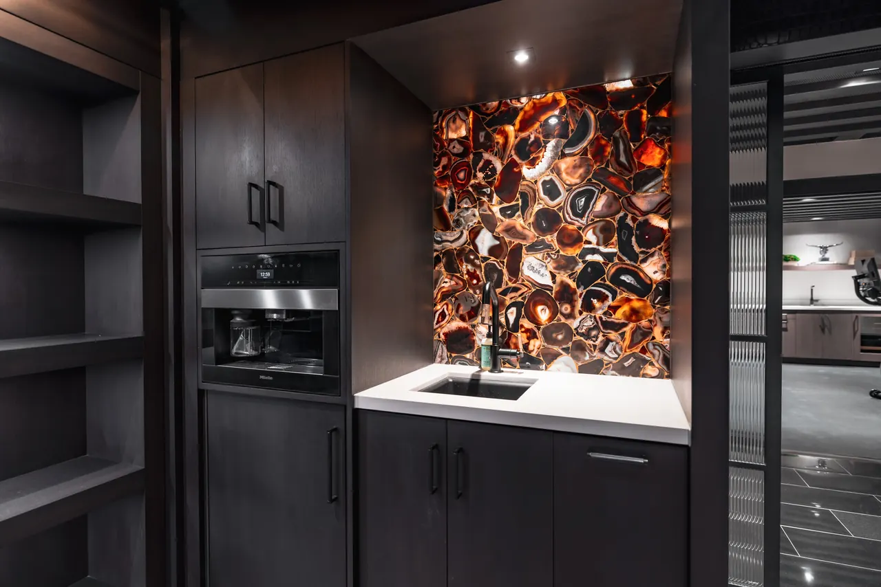 Dark timber pantry with a backlit agate feature panel and layered accent lighting