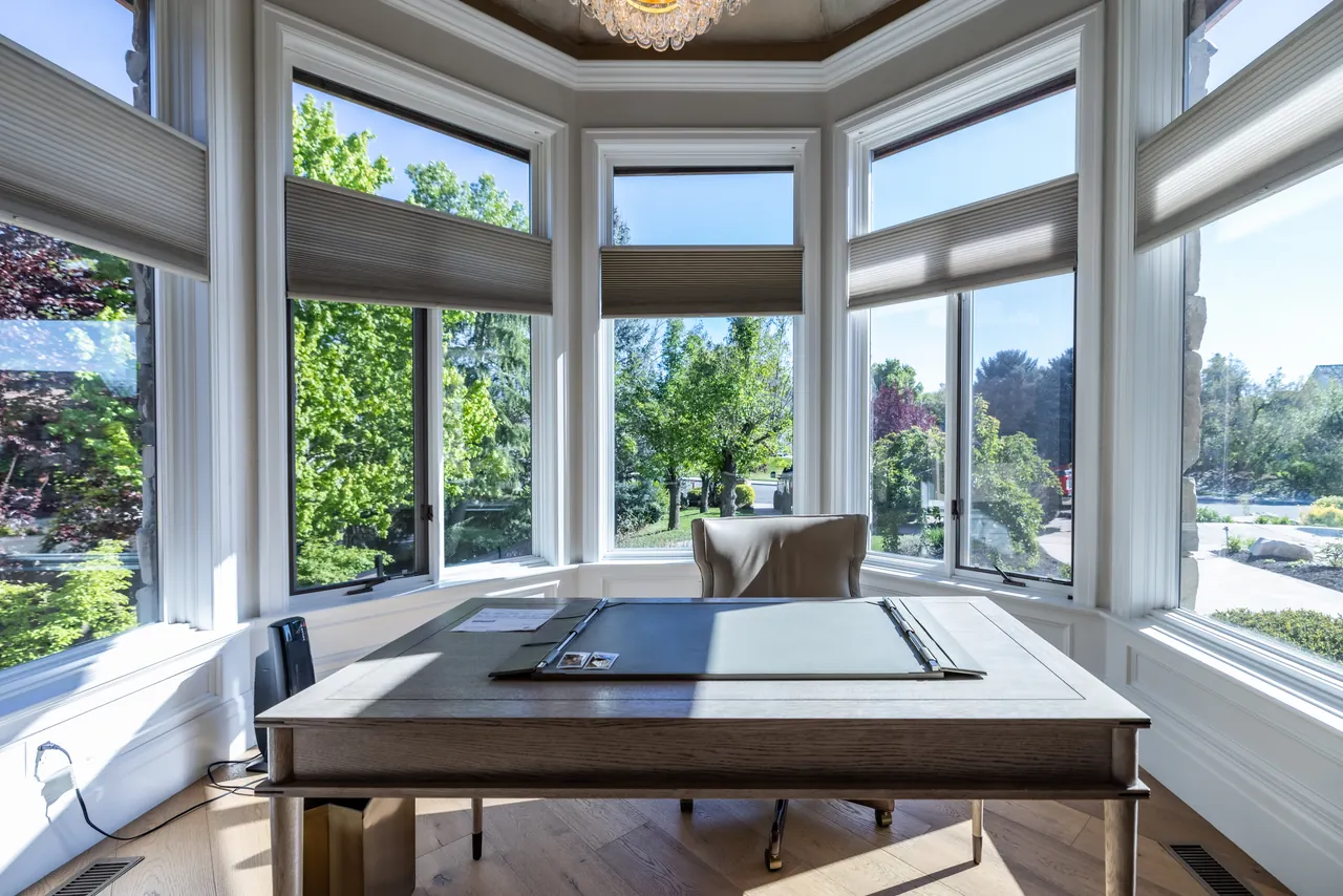 Sunlit home office with motorised cellular shades across a bay window