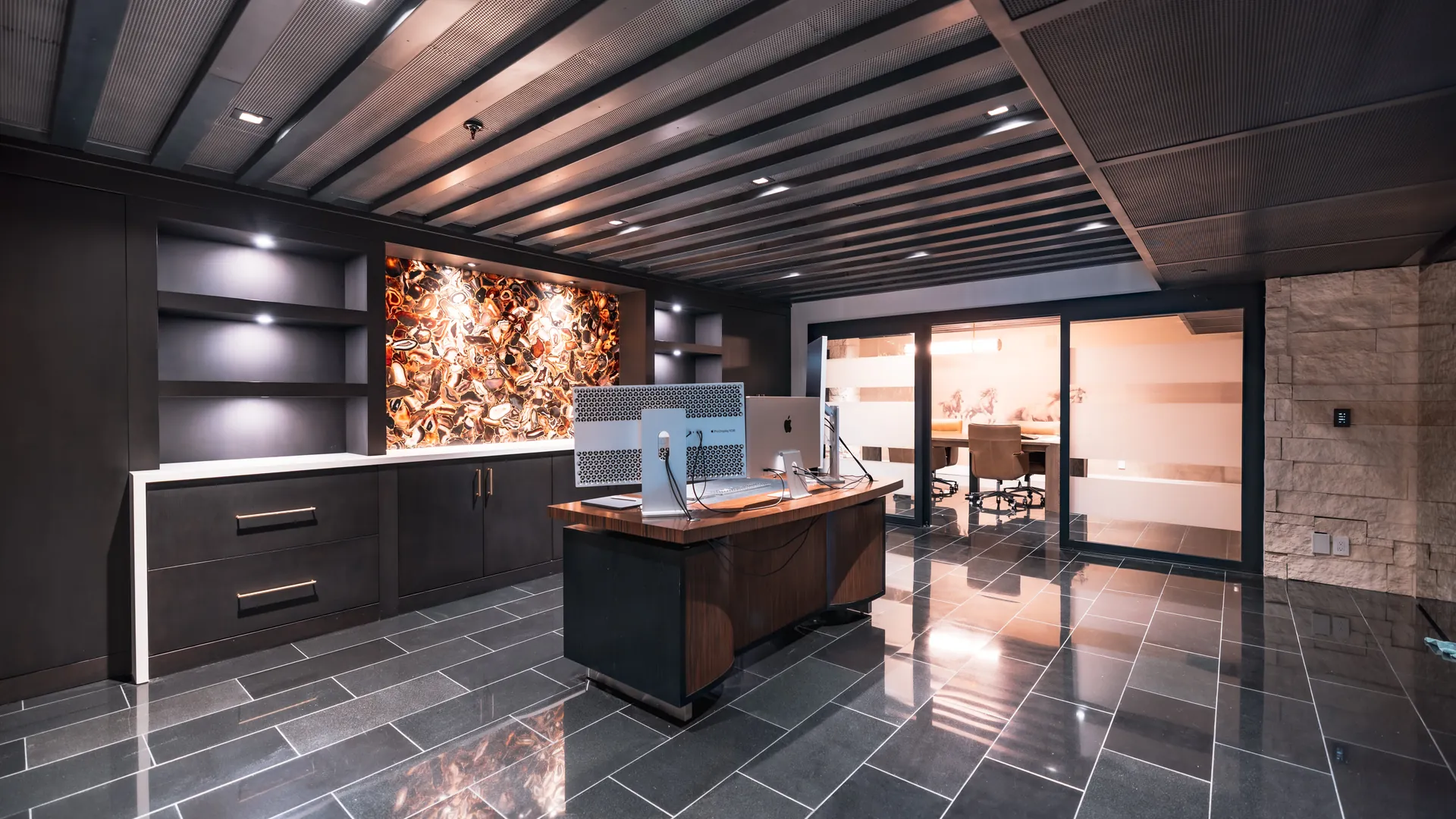 Dark executive office with a backlit agate feature wall and polished stone floor